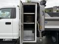 A 2021 Ford F-550 with an open storage compartment featuring metal shelves inside and a locking mechanism visible on the door