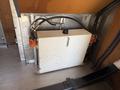 A white rectangular fuel tank with a black cap and two orange filters attached, located in the interior of a 2009 Kenworth T270