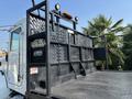 A 2020 Peterbilt 330 truck with a flatbed and roll-off system featuring a lattice design and safety lights mounted on the rear edge