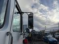A 2010 Autocar Xpeditor truck with a side mirror and a rearview mirror visible in the foreground