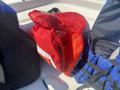 A red life jacket with reflective strips laid open on a boat seat