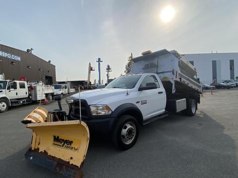 A white 2016 RAM 5500 truck with a black dump body and a yellow snow plow attached to the front