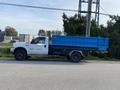 A white 2002 Ford F-550 truck with a blue dump bed parked on a road