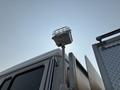 A 1999 Freightliner FL80 truck featuring a tall light fixture mounted on a pole at the rear of the cab