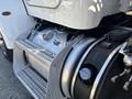 Close-up of the chrome fuel tank and access steps of a 2020 Peterbilt 330 showing detailed metalwork and safety labels