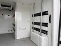 Interior of a 2020 RAM Promaster featuring metal shelving mounted on white walls and a gray rubber floor with two large storage compartments at the bottom