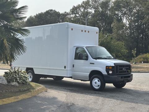 A white 2008 Ford Econoline van with a large cube-shaped cargo box attached to the rear