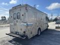 A silver 2009 Workhorse W62 vehicle featuring a boxy design with large rear doors and a cargo area, displaying a faded logo on the side and multiple windows on the back