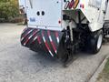 A 2012 International DuraStar 4300 street sweeper with a large rotary broom and reflective rear panels