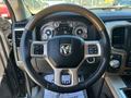 A close-up view of the steering wheel of a 2015 RAM 1500 featuring wood trim and several control buttons along with a cluster of gauges displayed behind the wheel