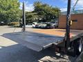 A 2014 RAM 5500 flatbed truck with a lowered loading ramp showcasing a wooden platform and metallic surface