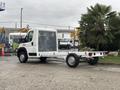 A 2023 RAM Promaster 3500 chassis cab with a clear protective covering on the front and an empty flatbed for cargo