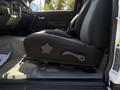A side view of the driver's seat in a 2011 Chevrolet Colorado showing the seat adjustment lever and fabric upholstery