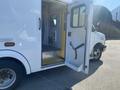 A 2011 Chevrolet Express ambulance with an open side door revealing the interior space and a seatbelt on the floor