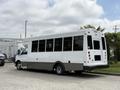 A 2020 Chevrolet Express bus with a white exterior and large windows, featuring a gray stripe along the lower body and a rear step for entry