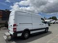 A 2016 Mercedes-Benz Sprinter van in white with a rear loading step and alloy wheels parked at a location with other vehicles in the background