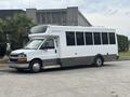 A white 2020 Chevrolet Express with black accents designed as a shuttle bus featuring large windows and a high roof