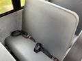 A gray bench seat with seat belts in a vehicle interior