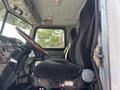 Interior view of a 2008 Peterbilt 340 showing the driver's seat and dashboard with wooden steering wheel and black fabric upholstery