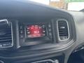 The dashboard of a 2015 Dodge Charger featuring a media display with radio station information and controls for audio tuning