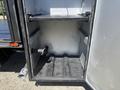 An empty storage compartment of a 2011 International 4300 with metal shelves and a pipe fitting on the left side