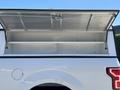 A 2019 Ford F-150 with an open truck bed cover revealing an empty storage compartment inside