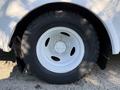 A white wheel of a 2016 Ford Econoline featuring a sturdy black tire with a deep tread pattern