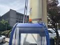 A 2023 Bitimec SC415 with a blue and transparent cabin features an orange flashing light on top and a round spotlight mounted on the front