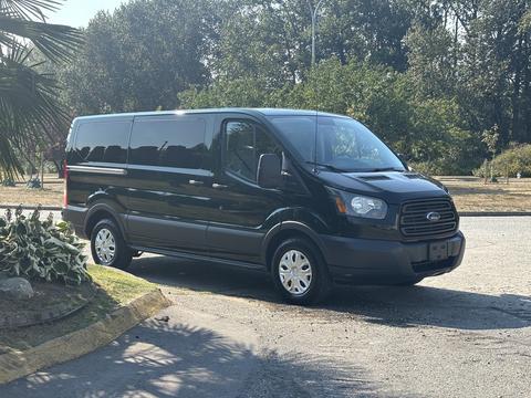 A black 2016 Ford Transit 150 van is parked at an angle showcasing its front and side features with a large windshield and five-spoke wheels