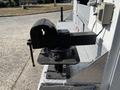 A heavy-duty black vise mounted on a metal surface with a crank handle for clamping and securing objects