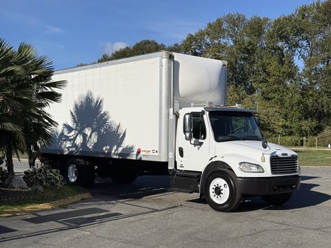A white 2012 Freightliner M2 106 box truck with a large cargo area is parked at an angle showcasing its front and driver's side