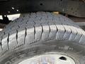 A close-up of a rugged off-road tire with deep treads designed for traction on various surfaces mounted on a wheel