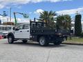 A white 2017 Ford F-550 flatbed truck with a black cargo bed and mesh sides parked in a lot