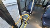 Interior view of a 2021 Ford Transit with yellow grab bar next to the door and blue upholstered chairs visible in the foreground