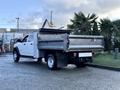 A white 2021 RAM 5500 pickup truck with a flatbed and rear dump feature parked at an outdoor location