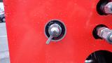 Close-up of a control knob labeled BO-KG, mounted on a bright red industrial machine with water droplets on the surface