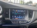 A 2018 Buick Encore dashboard displaying a touchscreen interface with radio stations and song information
