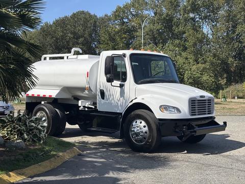 A white 2014 Freightliner M2 106 truck with a cylindrical tank mounted on the back and chrome wheels parked on a street