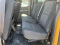 The interior of a 2013 Chevrolet Silverado 1500 showing a row of black cloth seats in the back with seatbelts and a clean floor space