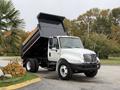 A white 2006 International 4200 dump truck with a raised black dump bed showcasing its capability for hauling and unloading materials