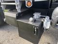 A 2013 Freightliner 114SD featuring a large black storage box with latch and a round valve on top along with a silver pipe adjacent to it
