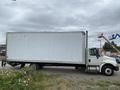 A 2014 International Durastar box truck with a plain white cargo area and a cab in front, parked on a gravel surface