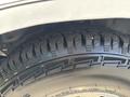 A close-up of the rugged tire of a 1995 Ford F-250 showcasing its tread pattern and details of the tire's sidewall