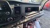 The interior of a 2021 Ford Transit displaying the dashboard controls a digital display and a small storage compartment