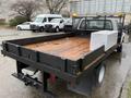 A 2008 Ford F-350 flatbed truck with a wooden bed and a toolbox on the side is parked with its tailgate down