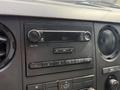 The interior dashboard of a 2011 Ford F-350 SD featuring a radio with buttons for volume and tuning and air conditioning controls