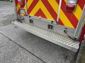 A 2007 Ford F-550 with a silver rear step and red and yellow reflective chevron pattern on the back