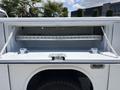 A 2021 RAM 5500 service truck with an open storage compartment featuring a shelf and securing straps
