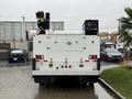 A 2024 RAM 5500 vehicle with a white body equipped with machinery and tools on the top and the rear featuring lights and safety markings