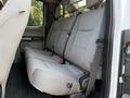 The image shows the rear seating area of a 2021 Ford F-350 SD with two bench seats covered in light gray fabric and equipped with seat belts